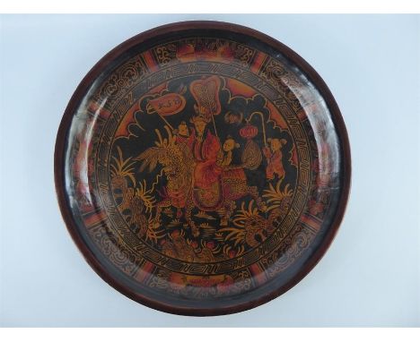 A Chinese Mid-20th Century Circular Wooden Tray, hand painted with a nobleman astride a temple dog, with foliate and fruit su
