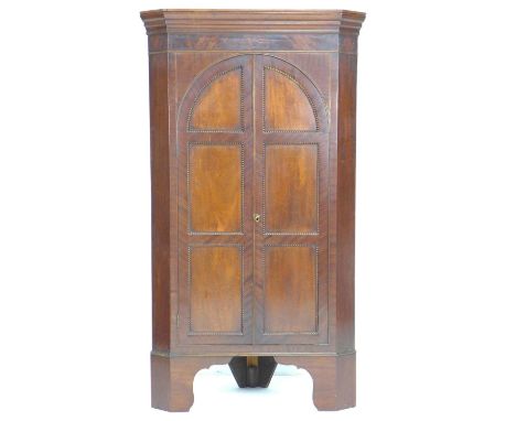 A Victorian mahogany freestanding corner cupboard, twin arched doors opening to reveal three fixed shaped shelves, raised on 