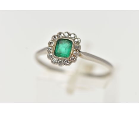 A WHITE METAL, EMERALD AND DIAMOND CLUSTER RING, centering on an emerald cut emerald, in a milgrain collet setting, within a 