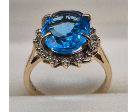 14ct yellow gold, diamond and large blue topaz gem stone ring. Oval form blue topaz surrounded by Diamond chips. 4.80grams. R