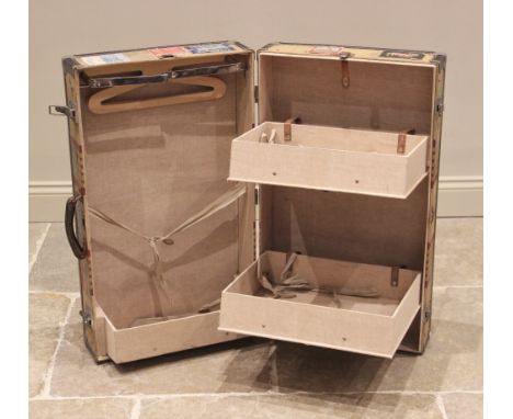 A vintage canvas fitted steamer trunk, early 20th century, applied with multiple hotel and travel stickers, opening to a fold