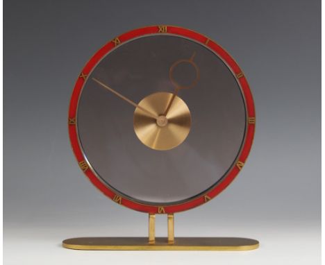 An Art Deco gilt metal and clear glass mantel timepiece, in the manner of Jaeger, the painted red bezel applied with relief c