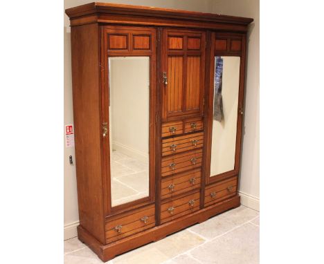 A late Victorian walnut Aesthetic Movement wardrobe, in the manner of Lamb, Manchester, the cavetto cornice above central cup