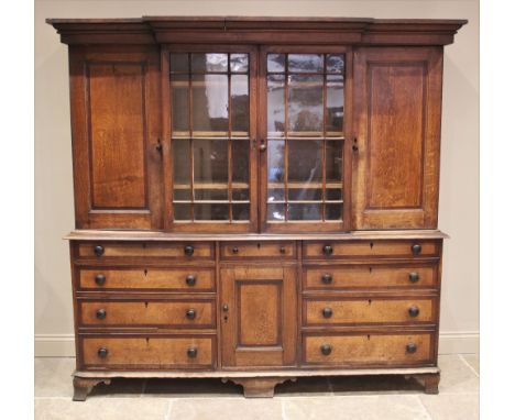 A George III oak and mahogany crossbanded breakfront housekeepers cupboard, the moulded cornice above a pair of astragal glaz