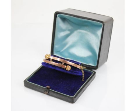 A Victorian gold coloured hinged bangle, the cross over front section with reeded spherical terminals, tongue and box snap fa