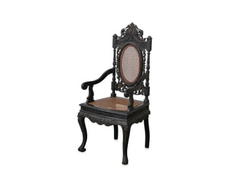A PERANAKAN CARVED AND EBONISED OPEN ARMCHAIR The back rest with squirrels and fruiting foliage, caned oval panel and seat, c