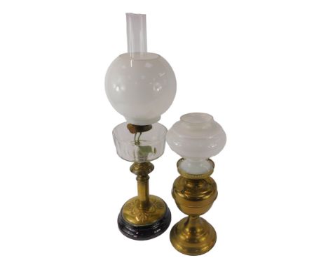 An early 20thC oil lamp, milk glass shade above a clear glass central reservoir, on an embossed brass column, on black socle 