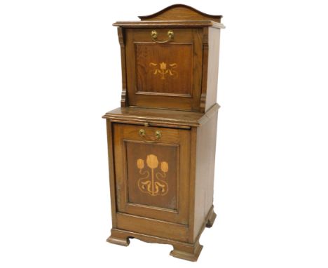An Art Nouveau oak and marquetry coal purdonium, the top with a raised back and a fall panelled fall decorated with a floral 