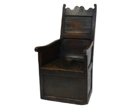 A 17thC elm wainscot commode chair, with a solid shaped back, solid arms and seat, with covered cylindrical recess on a block