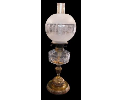 An early 20thC oil lamp, with a clear and etched glass globular shade, clear glass central reservoir, on a brass hour glass s