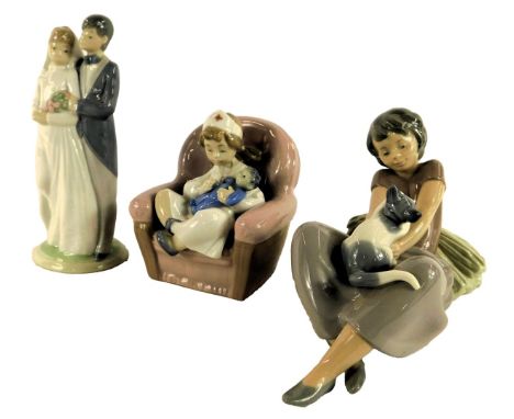 Three Nao porcelain figures, modelled as a girl wearing a nurse's uniform holding a child seated on a chair, 11cm high, a gir