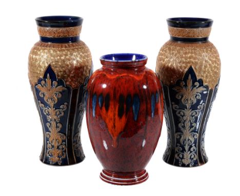  A pair of Royal Doulton Lambeth stoneware vases  , modelled in relief with panels of stiff-leaf foliage beneath a gilt whirl