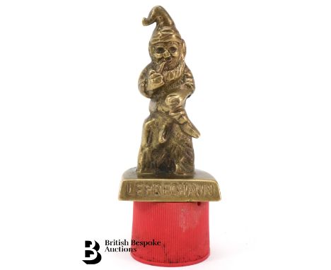 Leprechaun brass accessory mascot, featuring the famous Irish folklore character, sat smoking a pipe, wearing a hat.

-
