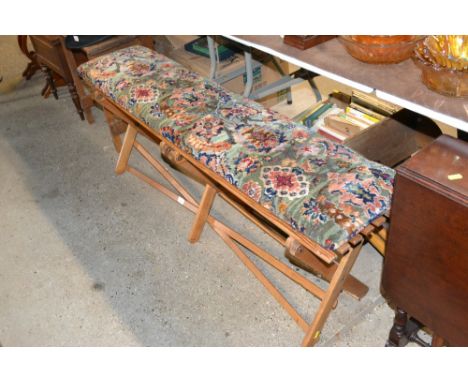 A Folding bench on X frame with rug covered seat