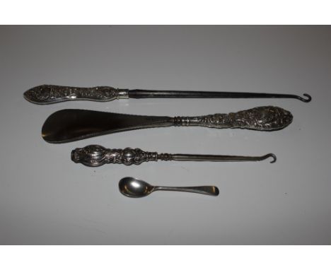 A silver handled long button hook; a smaller similar; a similar shoe horn and a silver condiment spoon 