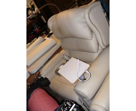 A reclining armchair upholstered in cream leather and complete with reading light and charging pad 