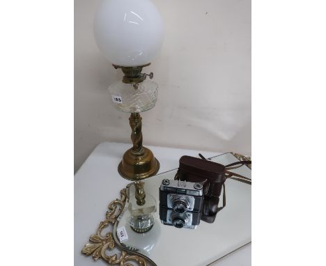 Bevelled edge wall mirror with pierced gilt cresting, an Ilford Sportsmans SLR camera and a brass oil lamp with clear reservo