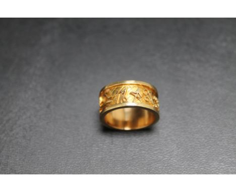 AN UNMARKED YELLOW METAL BAND, decorated text all around, approx weight 8.4g, ring size K 1/2