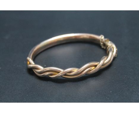 A GOLD AND COPPER BANGLE, having old repair with the three strand intertwined upper section having a 9ct stamp and the plain 