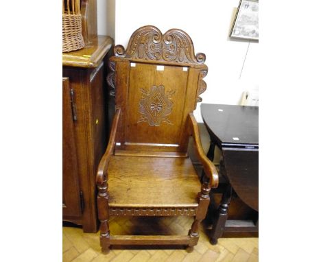 A 17th century style oak Wainscot armchair, with carved crest and panel back, fitted swept arms over a solid seat and turned 