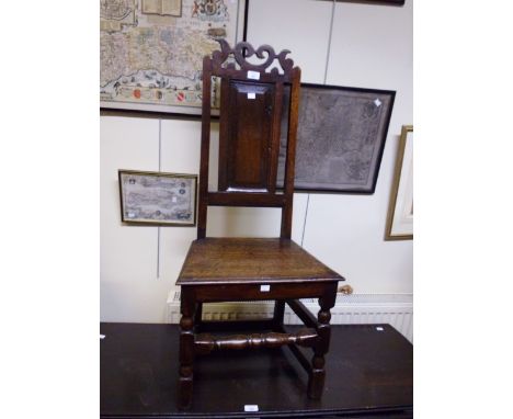 An early 18th century oak Lancashire type back stool, with shaped and pierced crest and panel back over solid seat and turned