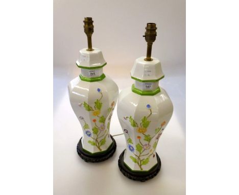 A pair of octagonal cream ceramic table lamps, each florally decorated in shallow relief