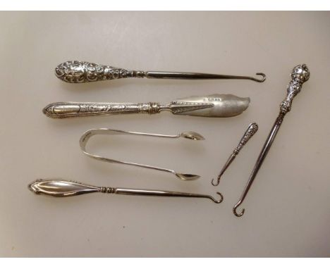 A small collection of silver handled button hooks, silver butter curl and sugar nips