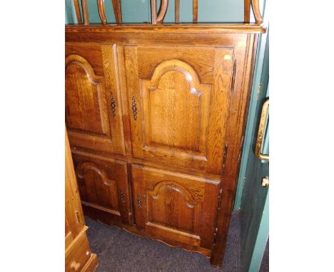 A reproduction oak tallboy, having two pairs of fielded panel doors on stile supports, 143 x 129cm