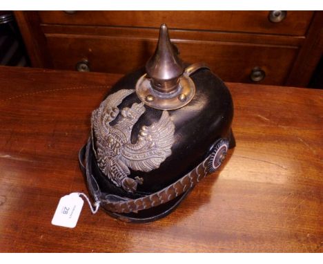 A brass mounted and shaped leather pickelhaube helmet, with chin strap and black finish, fitted with a spear form spike