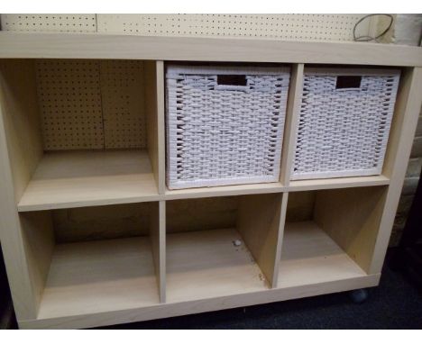 A light wood veneered storage system, fitted with white cane baskets