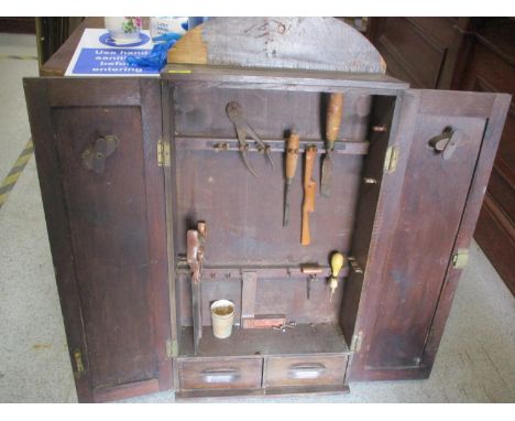 A 1930s oak finished, twin door, wall mounted tool cabinet, containing a small assortment of tools 