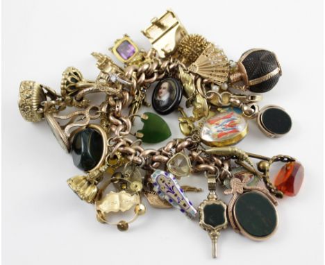 A huge and magnificent 9ct gold link bracelet suspending numerous 9ct, yellow metal and other charms to include fobs, seals, 