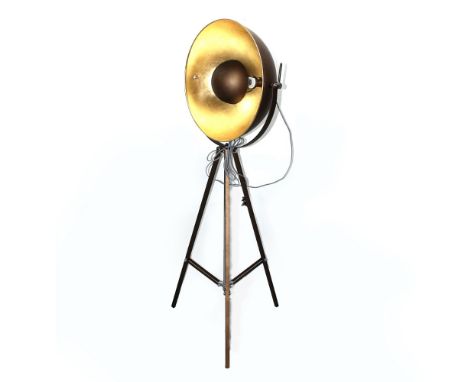 A contemporary floor-standing light in the form of a film studio spotlight, large bronzed dome with interior gold leaf, on a 