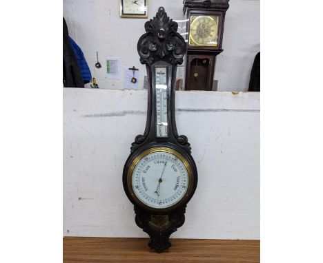 An early 20th century oak carved wall hanging barometer with an engraved brass plaque, 88cm h Location: 