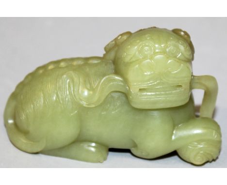 A CHINESE CELADON JADE-LIKE MODEL OF A BUDDHISTIC LION, with a few russetinclusions, 3.2in long.