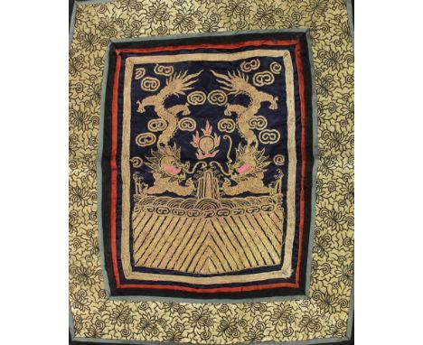 AN EARLY 20TH CENTURY CHINESE EMBROIDERED SILK PANEL, decorated to its centre with two dragons in gilt thread disputing a fla
