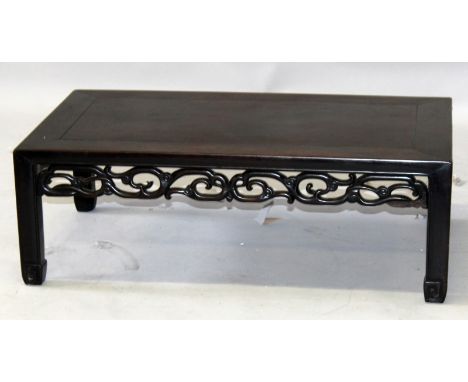 A 19TH CENTURY CHINESE CARVED HARDWOOD LOW RECTANGULAR TABLE, with a formal scroll frieze, 31.4in x 17.4in x 10.5in high.