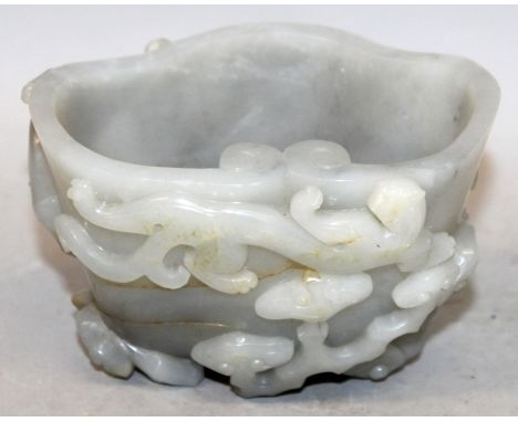 A CHINESE GREY JADE-LIKE LIBATION BOWL, the sides decorated in relief with a chilong and a bat above lingzhi, 4.7in long & 3.