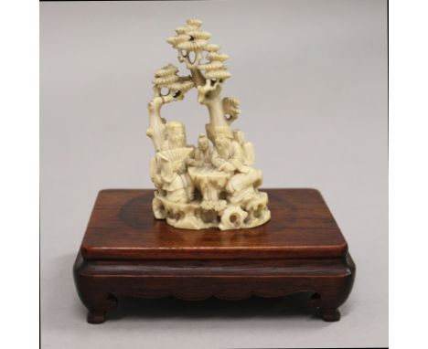 A 19TH CENTURY CHINESE IVORY CARVING OF SAGES IN A PINE GROVE, together with a good quality hardwood stand, the seated sages 