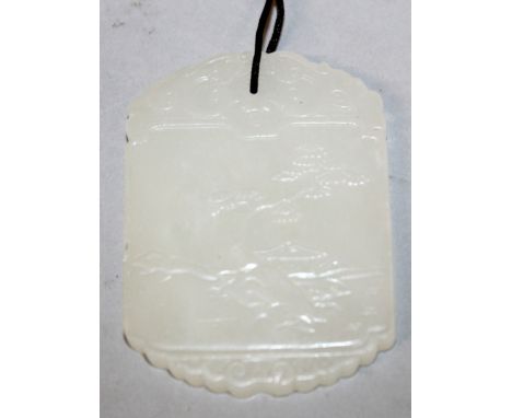 A CHINESE WHITE JADE PENDANT, decorated to one side with calligraphy, the reverse side with a pine tree and hut beside a rive