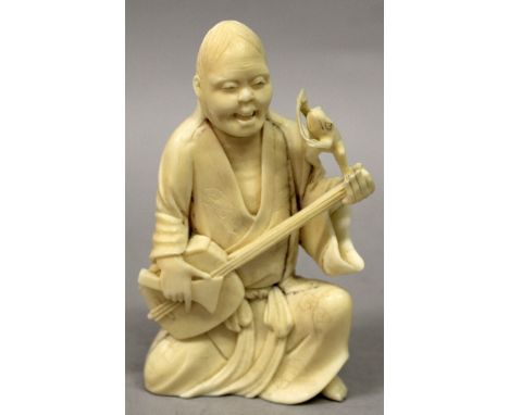 A JAPANESE MEIJI PERIOD IVORY OKIMONO OF GAMMA SENNIN, kneeling and playing a samisen and in the company of a toad reading a 