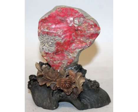 A CHINESE CHICKEN BLOOD SOAPSTONE STYLE BOULDER, supported on a fixed foliate stand, 4.25in wide at widest point & 4.8in high
