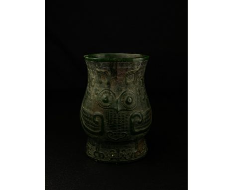 An archaistic Chinese Ming style spinach jade brush pot of baluster form carved with an abstract  stylised palace owl in reli