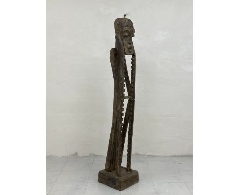 A tribal African style carved CD rack of figural form with a stylised head and an elongated body raised on a square plinth ba