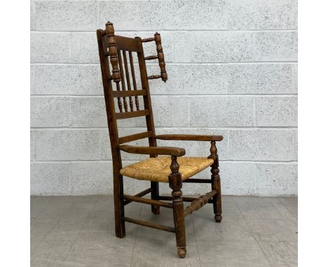 A 19th century elm Lancashire armchair having a curved top rail with a slatted and bobbin turned splat over a rush seat with 
