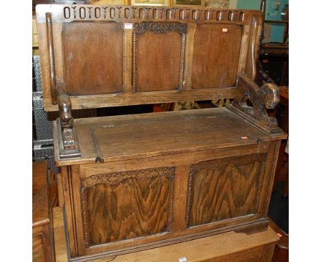 An early 20th century oak and beech twin panelled monks bench, having a fold over top with hinged box seat base, width 101cm