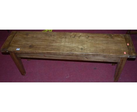 A stained pine bench, having cleated ends on tapering square supports, length 133cm