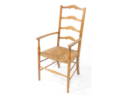 A stained beech ladder back open armchair, in Arts &amp; Crafts style with a rush seat, on turned supports.