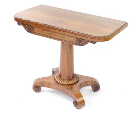 A Regency rosewood fold over card table, the frieze with acanthus scroll carving, raised on a turned column, over a quatrefoi