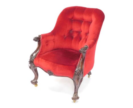 A Victorian rosewood armchair, upholstered in red button back velour, raised on cabriole legs, and scroll feet, with floral a